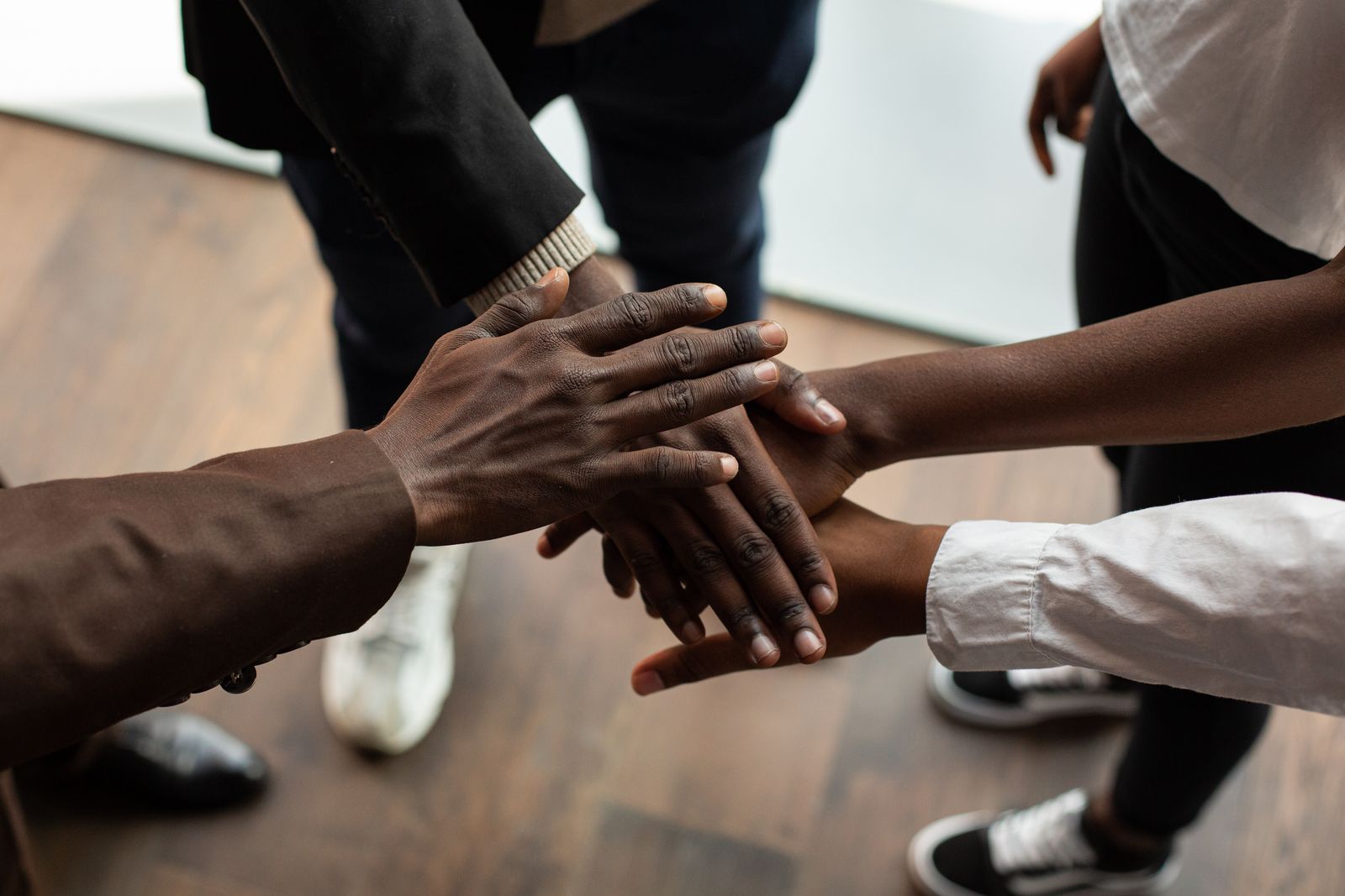 Volunteers’ hands stacked together in a huddle.