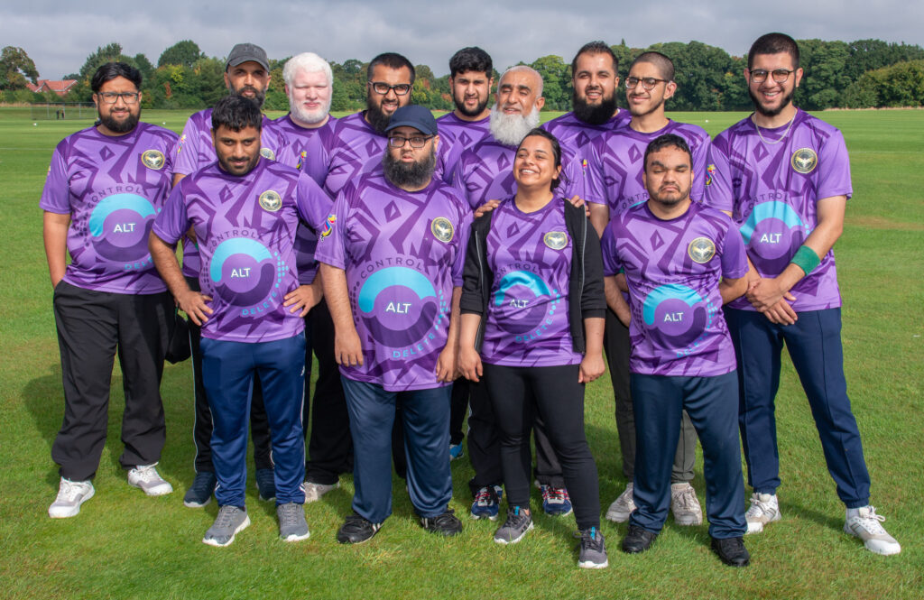The Greater Manchester Falcons squad in their purple kit, smiling together on a grass pitch after a match.